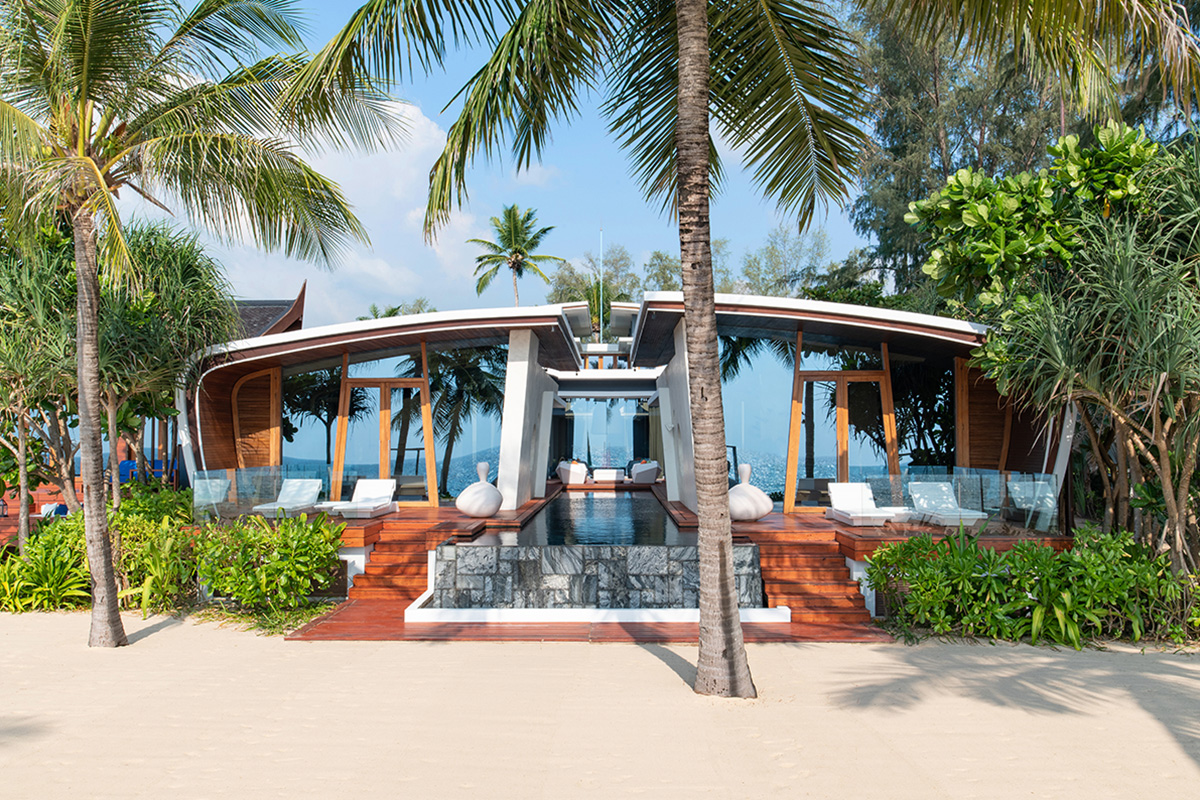 The facade of a beautiful villa on the beach surrounded by palm trees